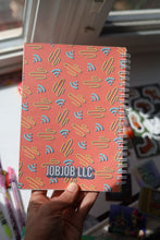 Load image into Gallery viewer, Hand holding the JobJob Reusable Sticker BookBook showing the JobJobLLC patterned coral cover — portable sticker organizer